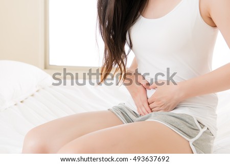 Beautiful asian woman suffering from stomach pain at home on bed, bedroom background, Physiological period concept