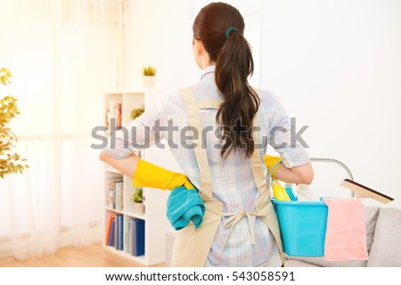 Young woman preparing to clean the living room window back face to camera at home. mixed race asian chinese model.