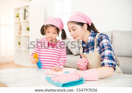 young asian woman and a little child girl wiped the dusting table in the living room at home. Mother and daughter do the cleaning in the house. family housework and household concept.