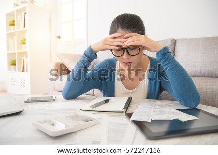 beauty asian stressed worried young woman is doing banking and administrative work holding bills at home sitting on sofa in the living room at home. interior and domestic housework concept.