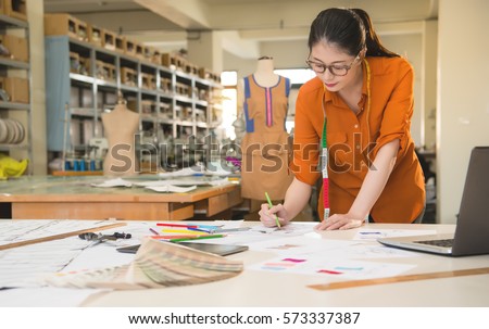 beautiful mixed race asian chinese woman designer drawing sketch for new season design in manufacturing office studio. profession and job occupation concept.