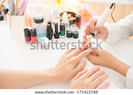female asian salon manicurist using portable pen shape electric nail drill art salon manicure file pedicure tool polish buffing for her customer