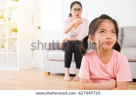 young lovely children was bored with her angry mother loudly nag feeling impatient hate annoying when mom was sitting behind her on sofa in living room at home.