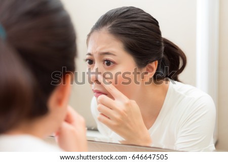 closeup photo of cute pretty lady after cleaning face looking at mirror checking nose having acne in bathroom before going to bed.