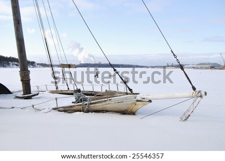 Bow of old wooden boat, sunk and frozen in a sea harbor.