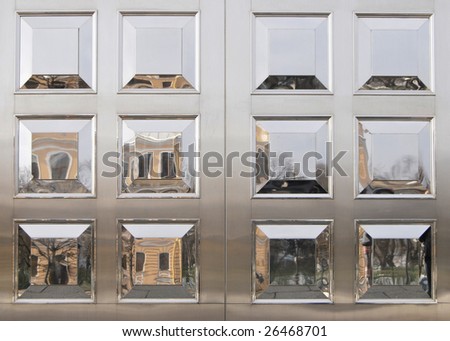 Street reflections in smooth polished panels of metal door.
