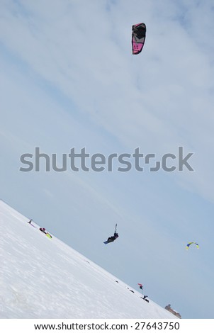 Kite boarding. High jump of sportsman over the plain snow surface.