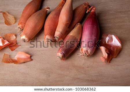 Shallots , a type of long pointed onion, ready for use as ingredients in cooking lying on a wooden surface