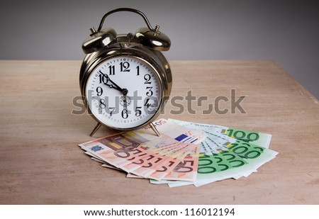 Time is Money concept shot with old mechanical Alarm Clock and Euro Banknotes