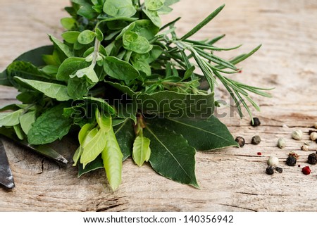 Thyme, Sage and Rosemary with Laurel bundled with cotton string and old rusty scissor on wooden board