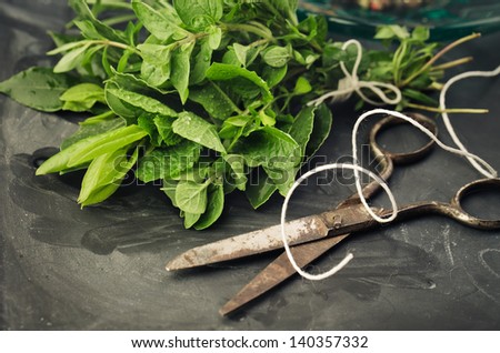 Thyme, Sage and Rosemary with Laurel bundled with cotton string and old rusty scissor on Slate board
