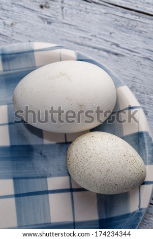 Egg of Goose And Duck on white and blue plate on wooden board