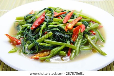 Thai food - quick fried water spinach with chili and soy sauce on wood background.