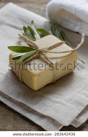 Handmade soap with olive oil decorated with olive tree leaves on a textile and wooden background