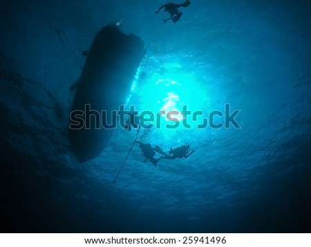 Submerged scuba diver surfacing to anchored boat