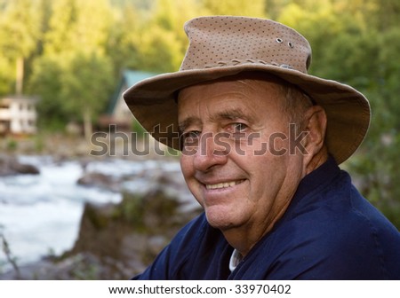 Active senior male fisherman with river close up with the river in the background.