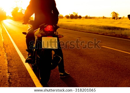 moped drivers on the road with sunset