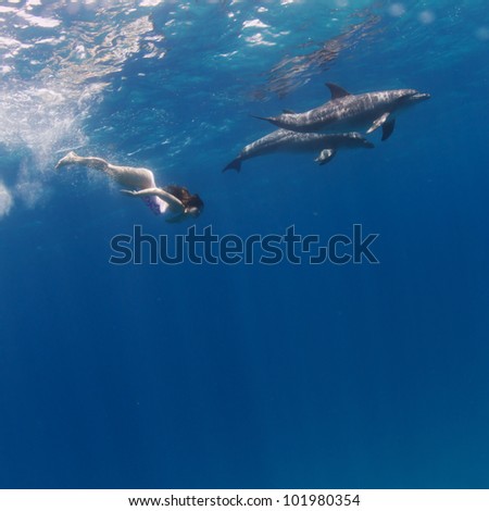 young model swimming with wild dolphins in open water