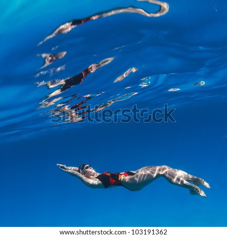 professional female swimming on back underwater  in blue water