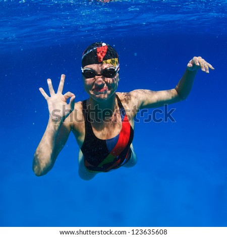 professional female sport master smiling underwater and showing ok sign