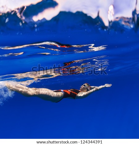 professional female swimmer moving on her back underwater in blue
