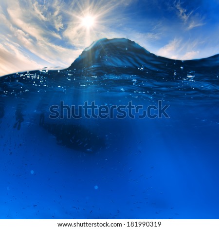 Cloudy sky with the sun split by waterline to underwater scene as design template.