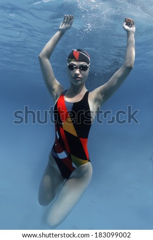 professional sport swimmer floating up underwater in blue with small air bubbles on her face