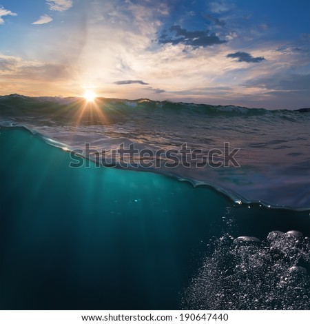 Beautiful ocean view with sunset behind breaking surfing wave over deep blue water for you design