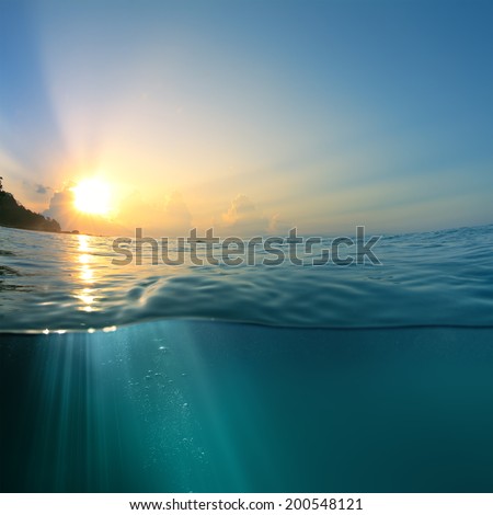 Beautiful sky with the sun image splitted by waterline. Air bubbles and sunrays underwater