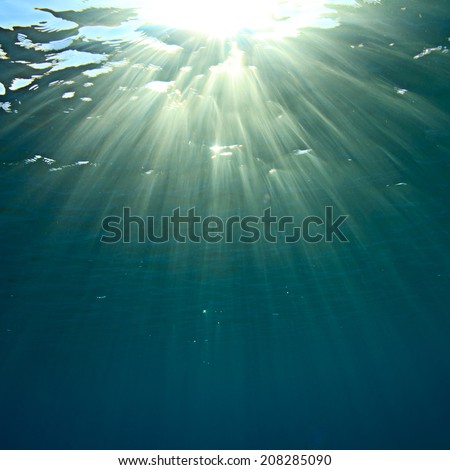 abstract underwater scenery sunrays going through water surface in deep blue sea