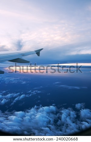 Wing of airplane from window on beautiful sunset cloudy background
