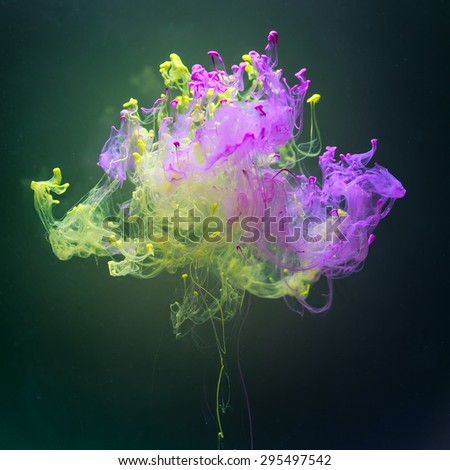 Pink and green complementary colors in fantastic shape. Colorful ink and paint spreading  underwater on dark green background.