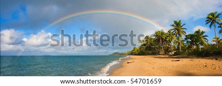 A Tropical Pacific oceanscape with palmtrees, rainbow, clouds