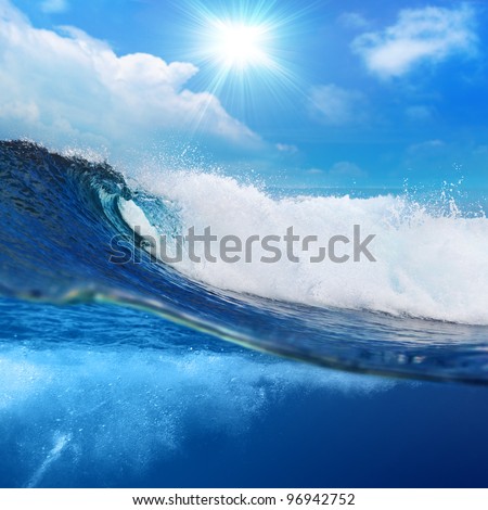 ocean-view seascape landscape Big surfing ocean wave splitted by waterline with slightly cloudy sky and the sun