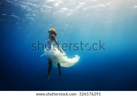 A girl wearing fashion white dress underwater in blue deep. A Wild Ocean Scenery without fish.