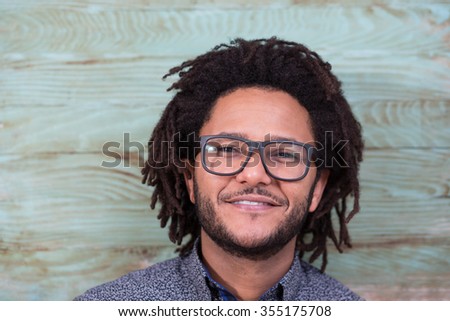 Studio portrait of cool black young man with black glasses, striped retro 70s shirt and retro afro hair on rustic background