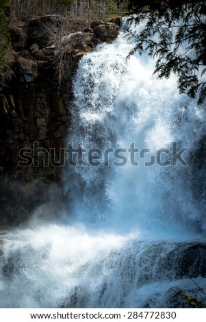 A waterfall and cliff. The Waterfall is frozen in time. Mist and spray erupt into the air.