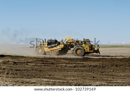 Earth movers in field with dust