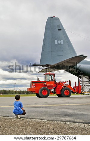 Small boy watching loader and plane