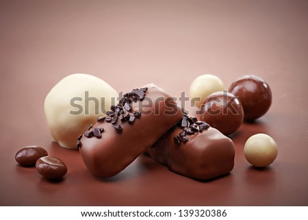 various chocolate candies on brown background