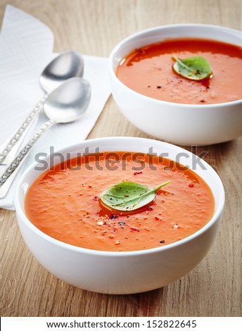 two bowls of tomato soup on wooden table