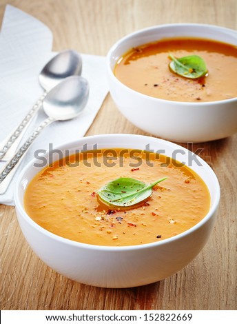 two bowls of squash soup on wooden table
