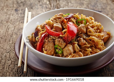 bowl of noodles with chicken and vegetables on wooden table