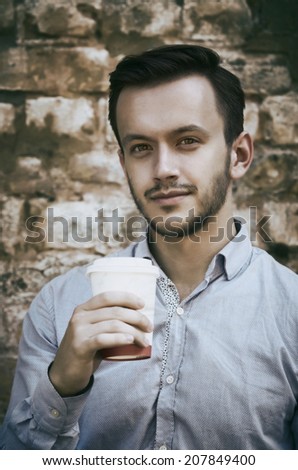 young man with take away coffee cup, sepia filtered image
