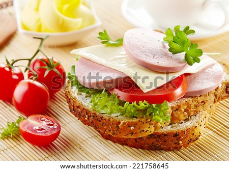breakfast sandwich with sliced sausage and tomato on kitchen table