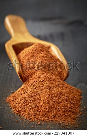 Scoop with ground cinnamon on wooden table