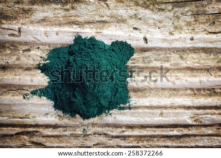 heap of spirulina algae powder on wooden background, top view