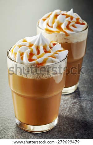 two glasses of coffee with whipped cream on dark table