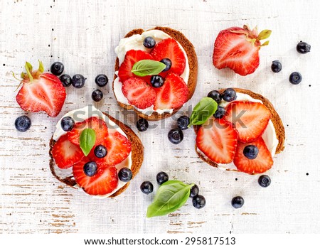 toasted bread with cream cheese and strawberries on white wooden table