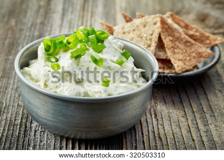bowl of cream cheese with green onions and herbs, dip sauce on wooden table